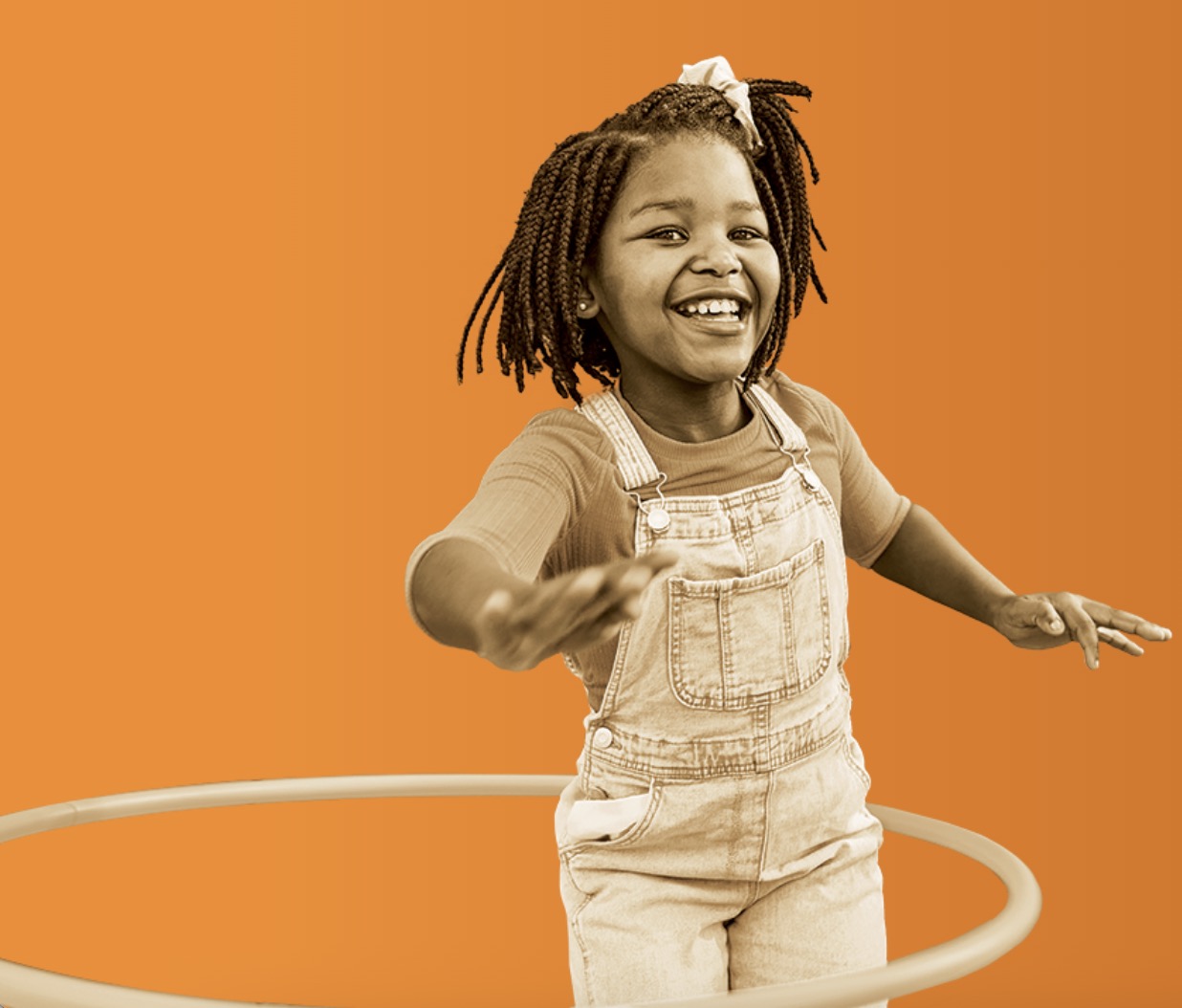 A smiling young girl playing with a hula hoop